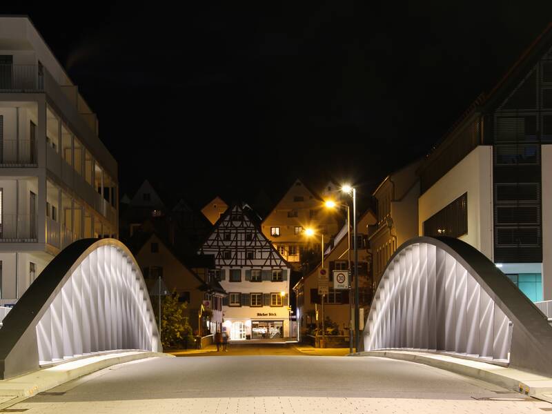 Beleuchtete Donaukanalbrücke bei Nacht vor dem Zugang zur Altstadt Riedlingen