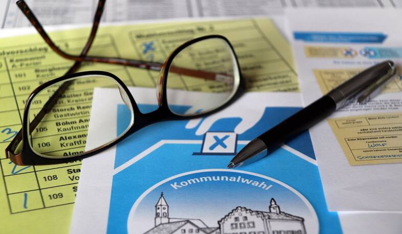 Stimmzettel, Brille und Kugelschreiber symbolisieren die Kommunalwahl
