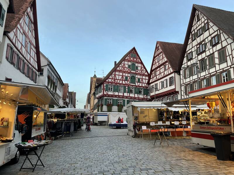 Der Riedlinger Marktplatz mit Fachwerkhäusern im Hintergrund und Ständen im Vordergrund, die Kleidung und Essen anbieten.