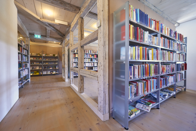Gefüllte Bücherregale in der Stadtbücherei im frisch renovierten Kapuzinerkloster mit weißem Fachwerk und heller Beleuchtung