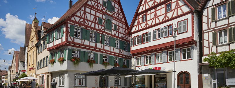 Marktplatz mit Sommerbestuhlung des Eiscafés und Fachwerkhäusern im Hintergrund