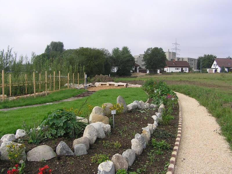 Oase der Gesundheit zeigt auf dem Foto den Barfußpfad, grüne Wiese und ein Kräuterbeet
