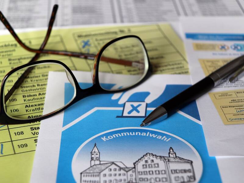 Stimmzettel, Brille und Kugelschreiber symbolisieren die Kommunalwahl