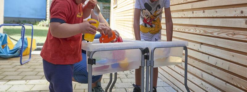 Spielende Kinder an einem Wasserspielgerät des Kindergartens Eichenau mit Schulkindergarten