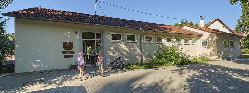 Kinder vor dem gepflasterten Eingangsbereich des Kindergartens Pflummern