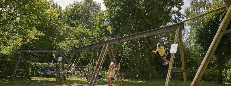 Spielwiese mit überschattetem Sandkasten der Kindertageseinrichtung Regenbogen