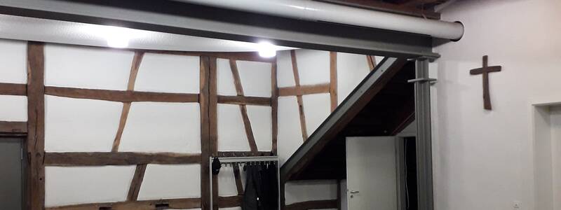 Seitenwand des Mehrzweckraums im Erdgeschoss des Kaplaneihauses mit Fachwerk und Garderobe